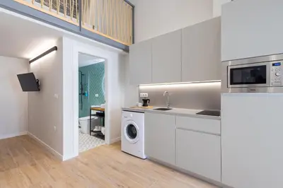 a kitchen with white cabinets and a washer and dryer at FLORIT FLATS - The Mediterranean Suites in Valencia