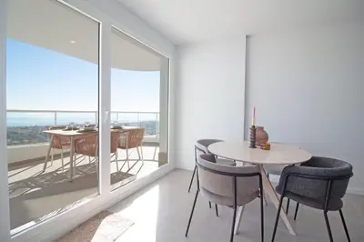 a dining room with a table and chairs and a large window at Global Vacacional, Moderno apartamento de dos terrazas con increíbles vistas al mar in Canet de Berenguer