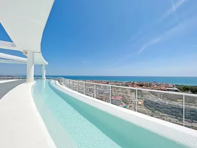 a swimming pool on the roof of a building with the ocean at Global Vacacional, Moderno apartamento de dos terrazas con increíbles vistas al mar in Canet de Berenguer