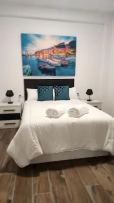 a bedroom with a white bed with a painting on the wall at Casa Valencia al mar in Valencia