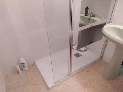 a shower with a glass door next to a sink at Habitación en la playa in Valencia