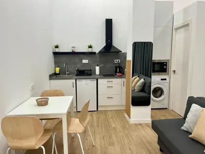 a kitchen and living room with a table and chairs at Loft cerca de playa y Ciudad de Artes y Ciencias in Valencia