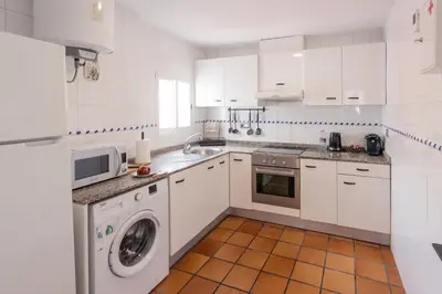 a white kitchen with a washing machine and a sink at Cozy Up Spain in Valencia