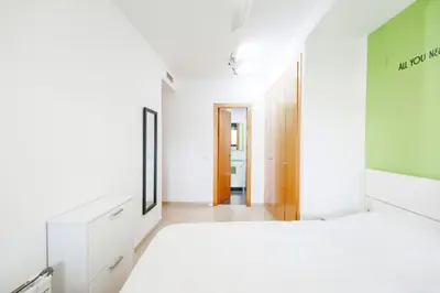 a white room with a bed and a hallway at Lujoso apartamento de dos habitaciones en la playa de Canet in Canet de Berenguer