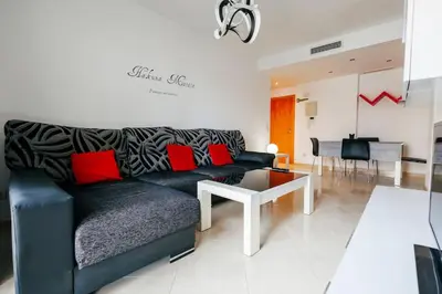 a living room with a black couch and red pillows at Lujoso apartamento de dos habitaciones en la playa de Canet in Canet de Berenguer