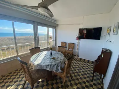 a dining room with a table and chairs and a large window at Primera línea de playa in Valencia