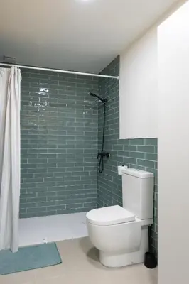 a bathroom with a toilet and a shower with green tiles at NEW BEACH flats VALENCIA in Valencia