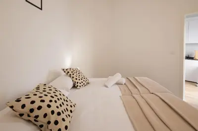 a white bed with black and white pillows on it at Cruz Cubierta Apartments in Valencia