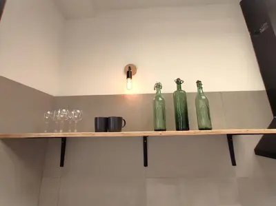 four green bottles sitting on a shelf with wine glasses at lifecoliving valencia loft A in Valencia