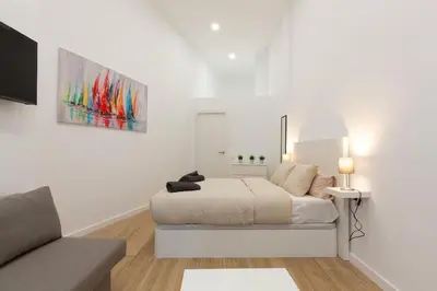 a white bedroom with a bed and a couch at Nuevo loft en playa y cerca del centro, AC y Wifi in Valencia