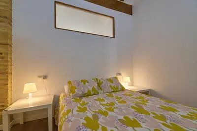 a bedroom with a bed and two tables with lamps at Apartamento minimalista en Matemático Marzal in Valencia