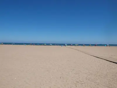 a sandy beach with a group of people in the ocean at Malvarrosa Las Arenas Access in Valencia