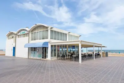 a building with tables and chairs in front of the beach at Malvarrosa Las Arenas Access in Valencia