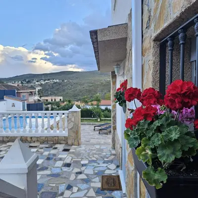a balcony with red flowers on a building at Chalet con piscina, barbacoa y jacuzzi en Valencia in Turís