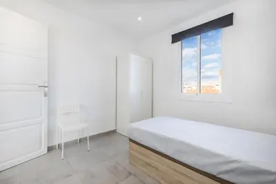 a white bedroom with a bed and a window at Placid Puerto in Puerto de Sagunto