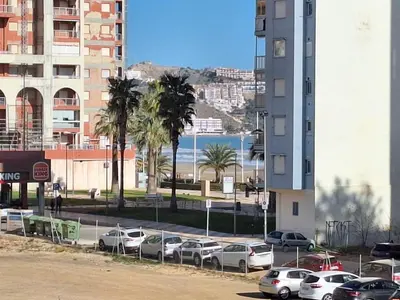a parking lot with cars parked in front of a building at Cullera Playa in Cullera