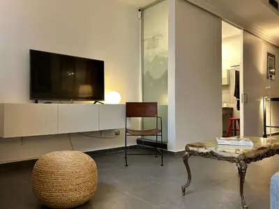 a living room with a tv and a chair and a table at Apartamento chic en Ciutat Vella in Valencia