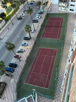 two tennis courts on a street with parked cars at Apto. Cullera vistas espectaculares primera línea in Cullera