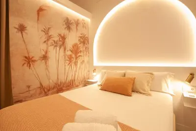 a bedroom with a white bed with a mural of palm trees at Estudio Bohemio Centro in Valencia