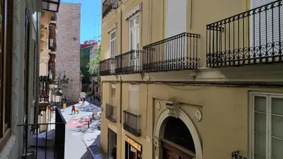 an alley with a building with an arch and balconies at Reina in Valencia