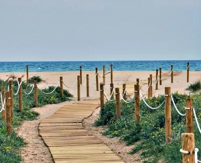 a wooden path leading to a beach with the ocean at UIM Mediterraneo Cendoya 4 Wifi in Puerto de Sagunto