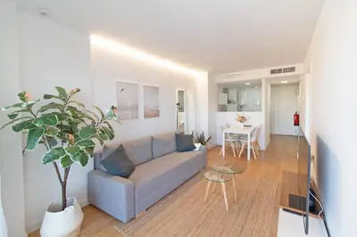 a living room with a couch and a table at Global Vacacional, Moderno apartamento con piscina y terraza en la playa de Canet in Canet de Berenguer
