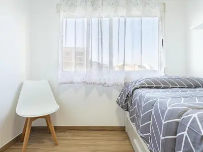 a bedroom with a bed and a chair next to a window at Apartment Orion-2 by Interhome in Cullera