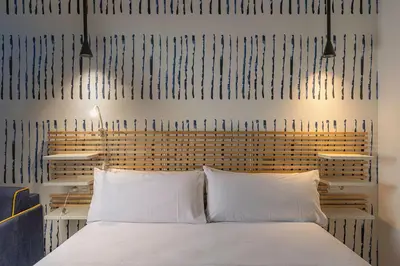 a bedroom with a white bed with two pillows at Gulliver Suites Valencia in Valencia