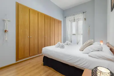 a bedroom with a large white bed with a wooden cabinet at Patacona Mediterranean Beach in Valencia
