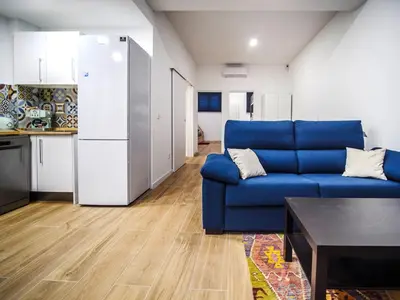 a living room with a blue couch and a kitchen at Apartamento Disfrutones Valencia in Valencia