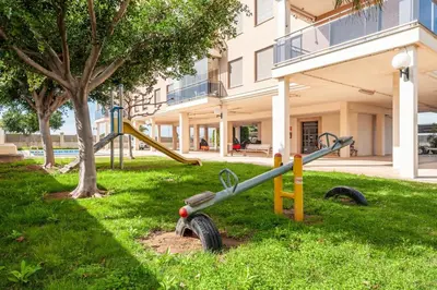 a playground in the grass in front of a building at Burriana Beach Retreat: Pool & Comfort in Burriana