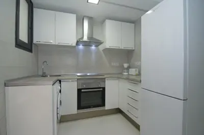 a kitchen with white cabinets and a sink and a refrigerator at Calm Company in Valencia