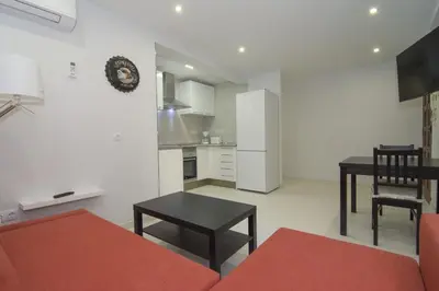 a living room with a table and a kitchen at Calm Company in Valencia