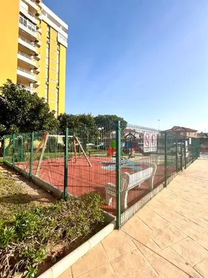 a chain link fence with a playground with swings at Apartamento en la Playa Canet, muy cerca de Valencia in Canet de Berenguer