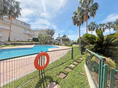 a fence next to a swimming pool with palm trees at Global Vacacional, Planta Baja con Piscina en Canet de Berenguer in Canet de Berenguer