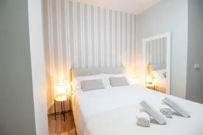a white bedroom with a white bed and two lamps at Suite Parque del Turia by Concept Flats in Valencia