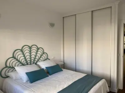 a bedroom with a large bed with two blue pillows at Acogedor apartamento en primera línea de playa in Canet de Berenguer