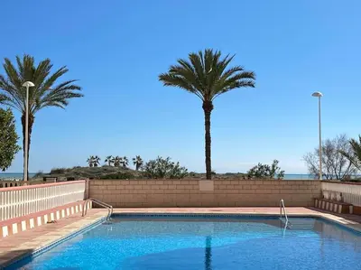 a swimming pool with two palm trees in the background at Acogedor apartamento en primera línea de playa in Canet de Berenguer