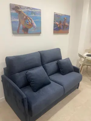 a blue couch in a living room with paintings at Mar&Sol Flats by Vivo GC in Valencia
