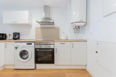 a white kitchen with a washer and dryer at Canet Seaview Gem: Pool & Beach Proximity in Canet de Berenguer