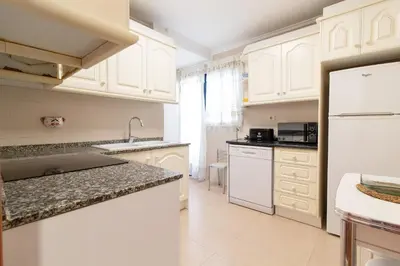 a kitchen with white cabinets and a white refrigerator at Global Vacacional, Apartamento cerca de la playa en Puerto Sagunto in Puerto de Sagunto