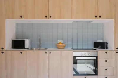 a kitchen with wooden cabinets and a stove and microwave at Coliving La Alfareria in Valencia