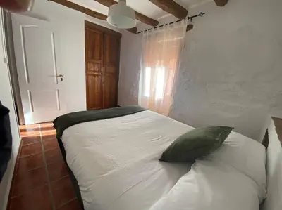 a bedroom with a white bed with a green pillow at Apartamentos Ca Federo, Casa la Tía Elena in Losa del Obispo