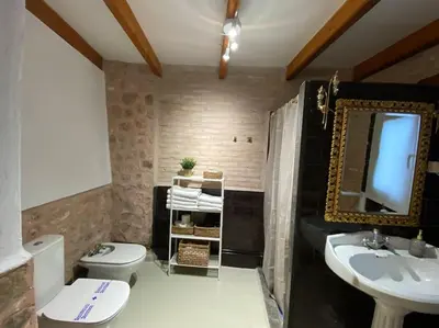 a bathroom with a toilet and a sink and a mirror at Apartamentos Ca Federo, Casa la Tía Elena in Losa del Obispo