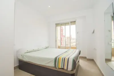 a bed in a white room with a window at Relaxing Reina in Valencia