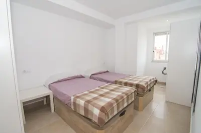 a bedroom with two beds and a table and a window at Relaxing Reina in Valencia