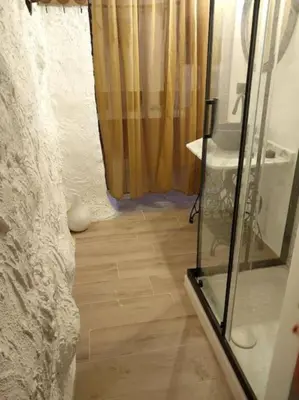 a bathroom with a glass shower and a wooden floor at La casita del Horno in Pedralba
