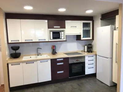 a kitchen with white cabinets and a sink and a refrigerator at Apartamento ARENSOL EN PRIMERA LINEA DE PLAYA in Cullera