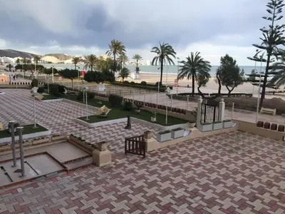 a park with palm trees and a beach at Apartamento ARENSOL EN PRIMERA LINEA DE PLAYA in Cullera