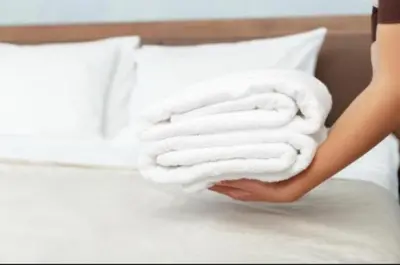 a woman is holding a stack of towels on a bed at UIM Mediterraneo PB Cendoya 1 wifi in Puerto de Sagunto